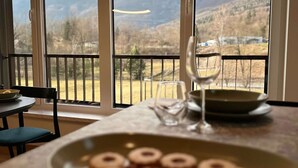 Un espace repas offrant une vue sur les montagnes grâce à de grandes fenêtres.