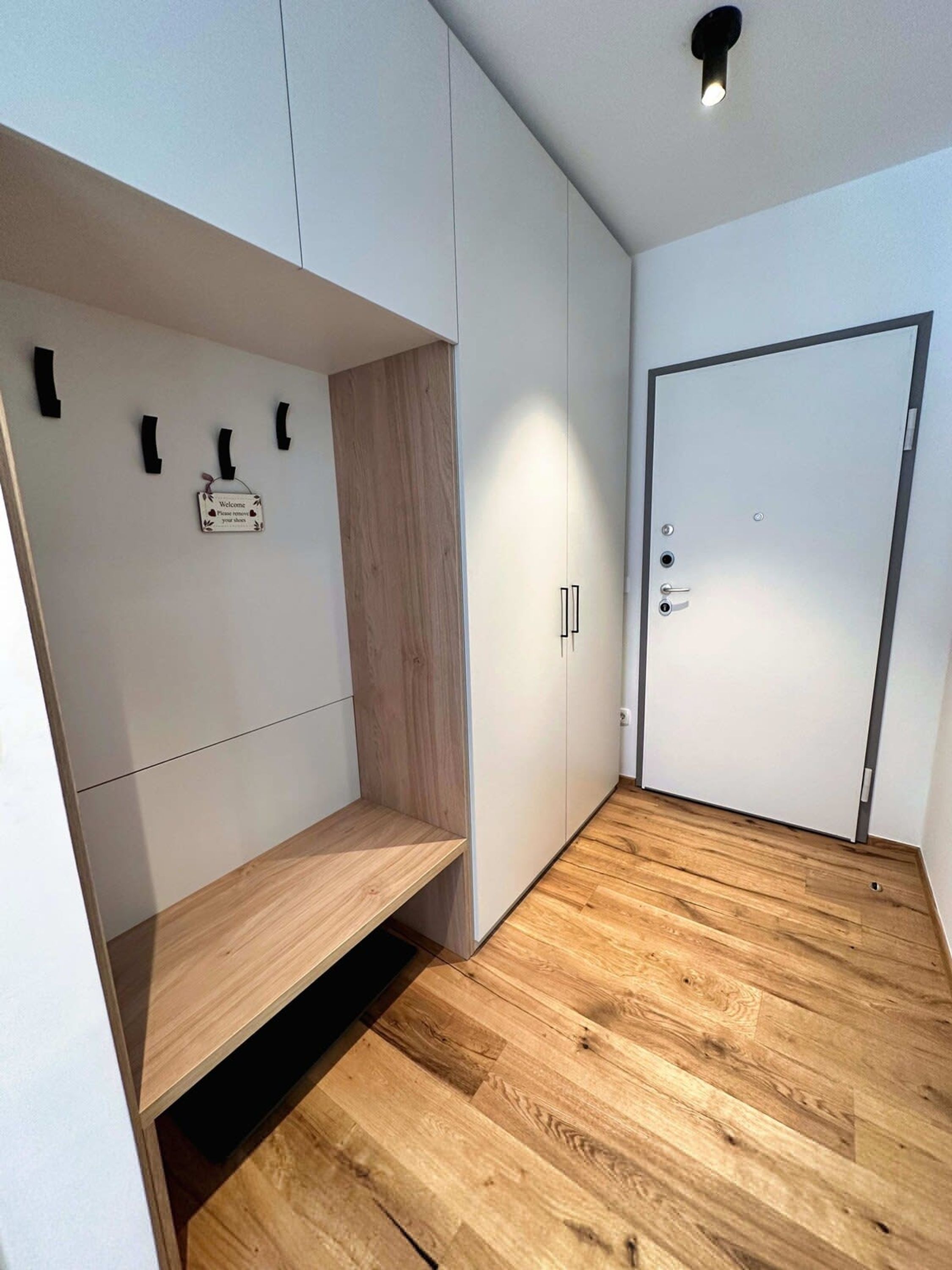 A modern, minimalist room with a wooden floor, white walls, and a door with a handle.