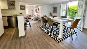 A modern kitchen with a built-in dishwasher, a dining area with a large table and chairs, and a living room with a sofa and decorative items. - Casa Con Vista - Stunning Villa in Moraira (Teulada)