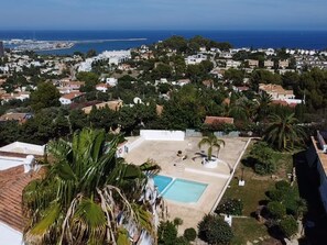 A residential area with a large swimming pool surrounded by greenery and palm trees. - Casa Clare - 3 Bedroom Apartment in Denia (Denia)