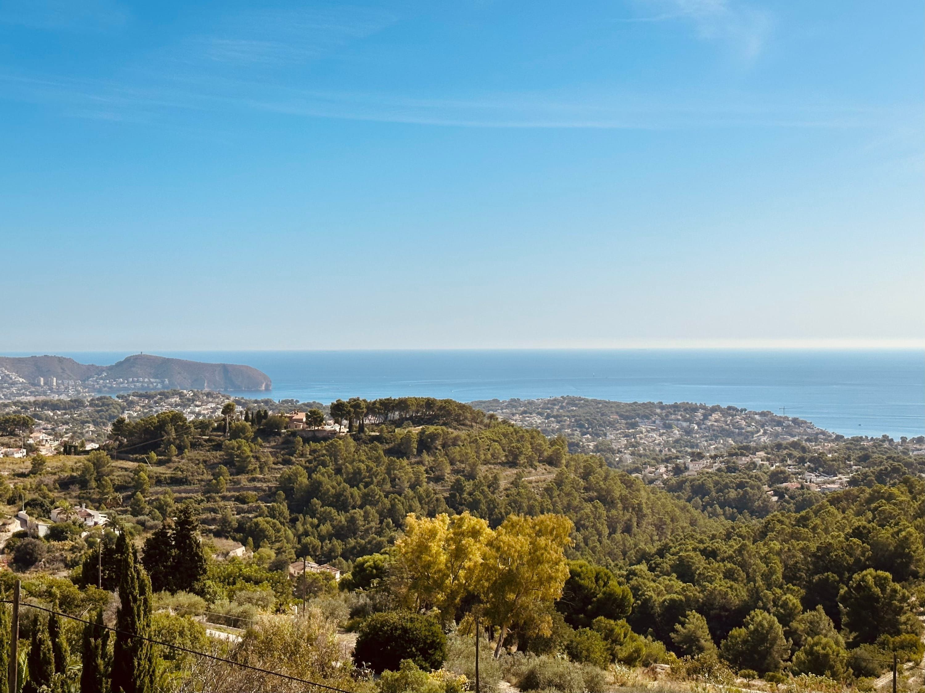 A coastal landscape with a view of the sea and a town in the distance.