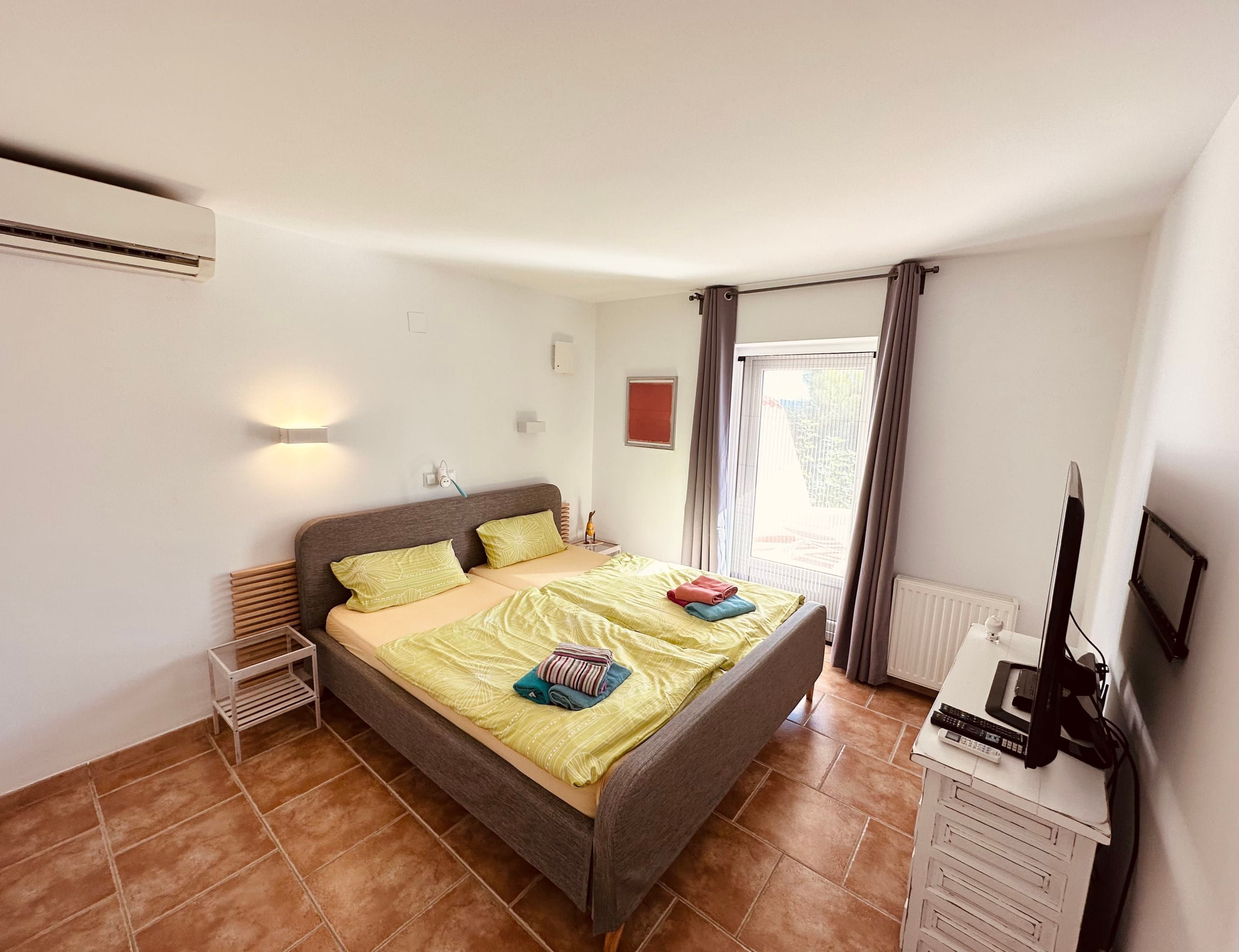 A bedroom with a bed, a TV, and a radiator.