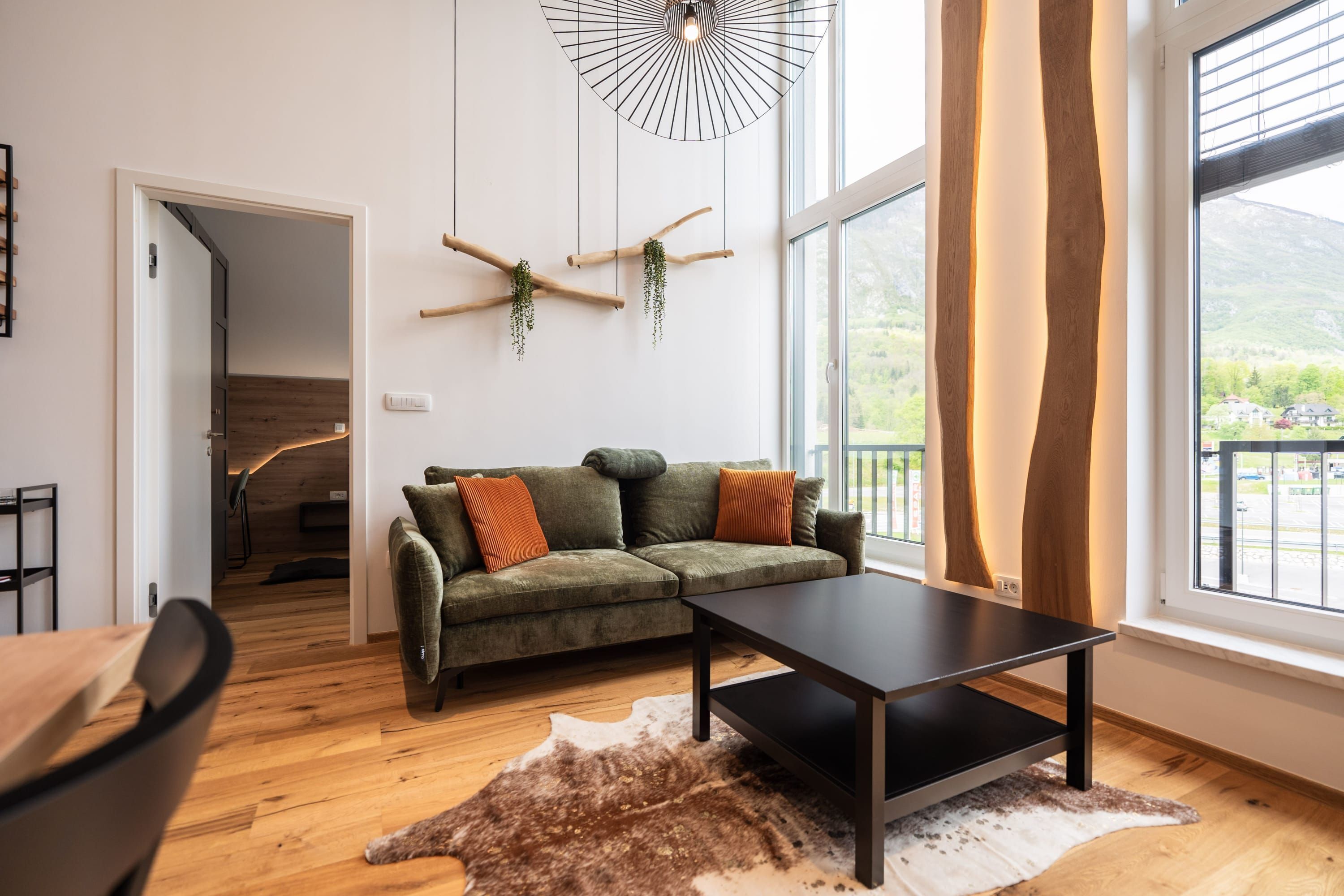 Una sala de estar moderna con un sofá modular, una mesa de centro y un ventanal con vistas a las montañas.