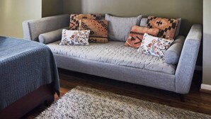 A cozy room with a grey sofa, patterned cushions, and a window with a white frame. - Apt3 Edenbrae- Featured in Birmingham Magazine (Birmingham)