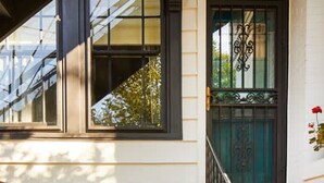 A front porch with two chairs, a small table, and a decorative railing. - Apt3 Edenbrae- Featured in Birmingham Magazine (Birmingham)