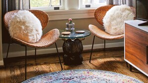 A room with two wicker chairs, a small round table with a candle, and a television on a wooden cabinet. - Apt3 Edenbrae- Featured in Birmingham Magazine (Birmingham)