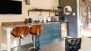A modern kitchen with two bar stools, a microwave, and a coffee maker.