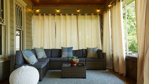 Una sala de estar acogedora con un sofá modular, un otoman redondo y una mesa de centro con una planta.