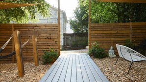 Una terraza de madera con una hamaca, una estatua y una silla.