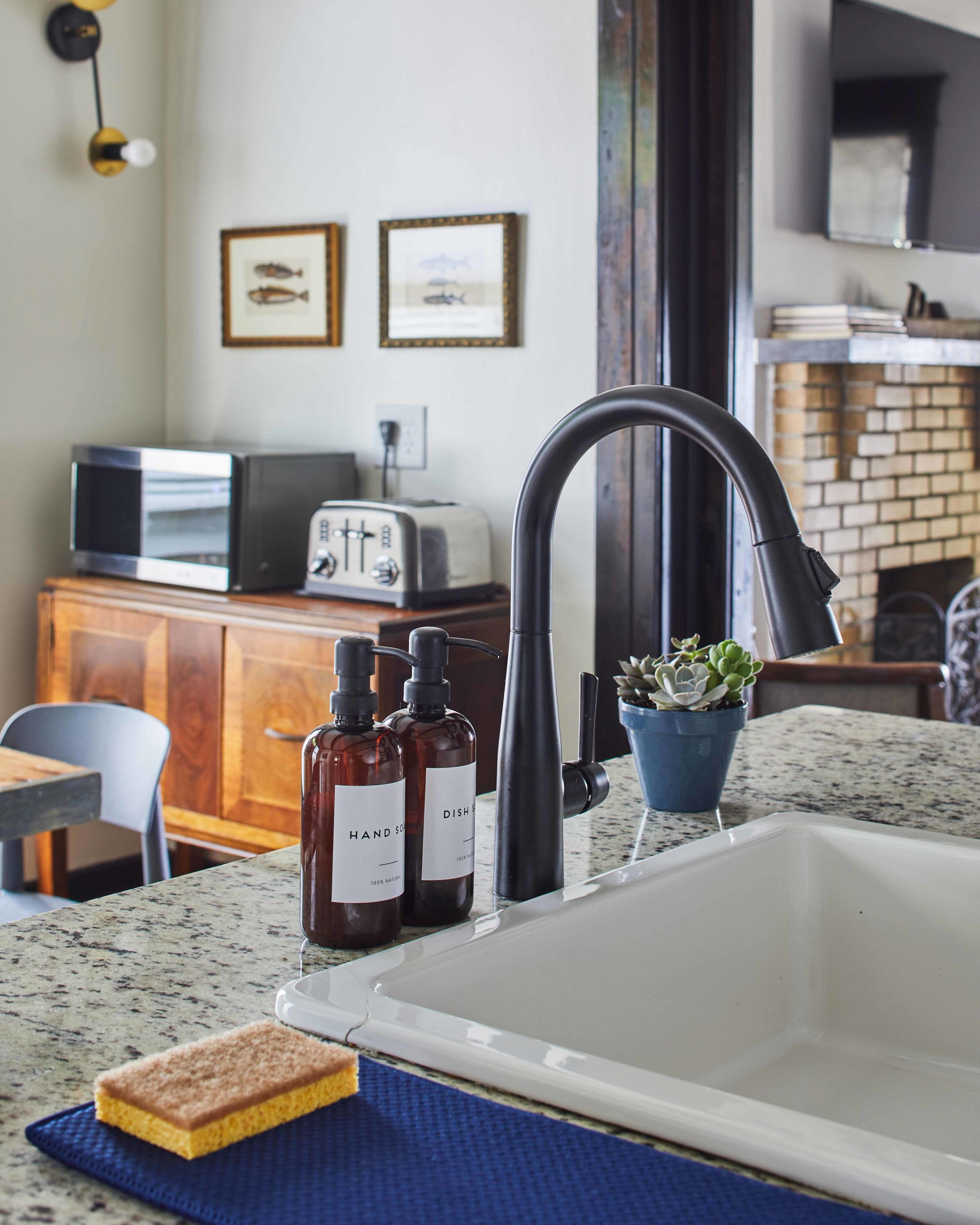 A kitchen with a modern sink, a toaster, and a potted plant.