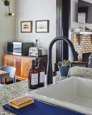 A kitchen with a modern sink, a toaster, and a potted plant.