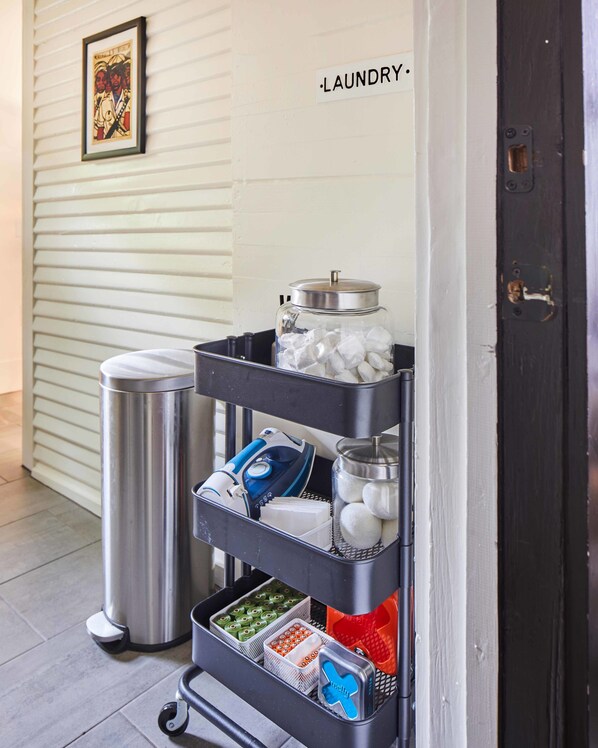 A laundry cart with various items including a trash can, a container with ice, and storage bins.