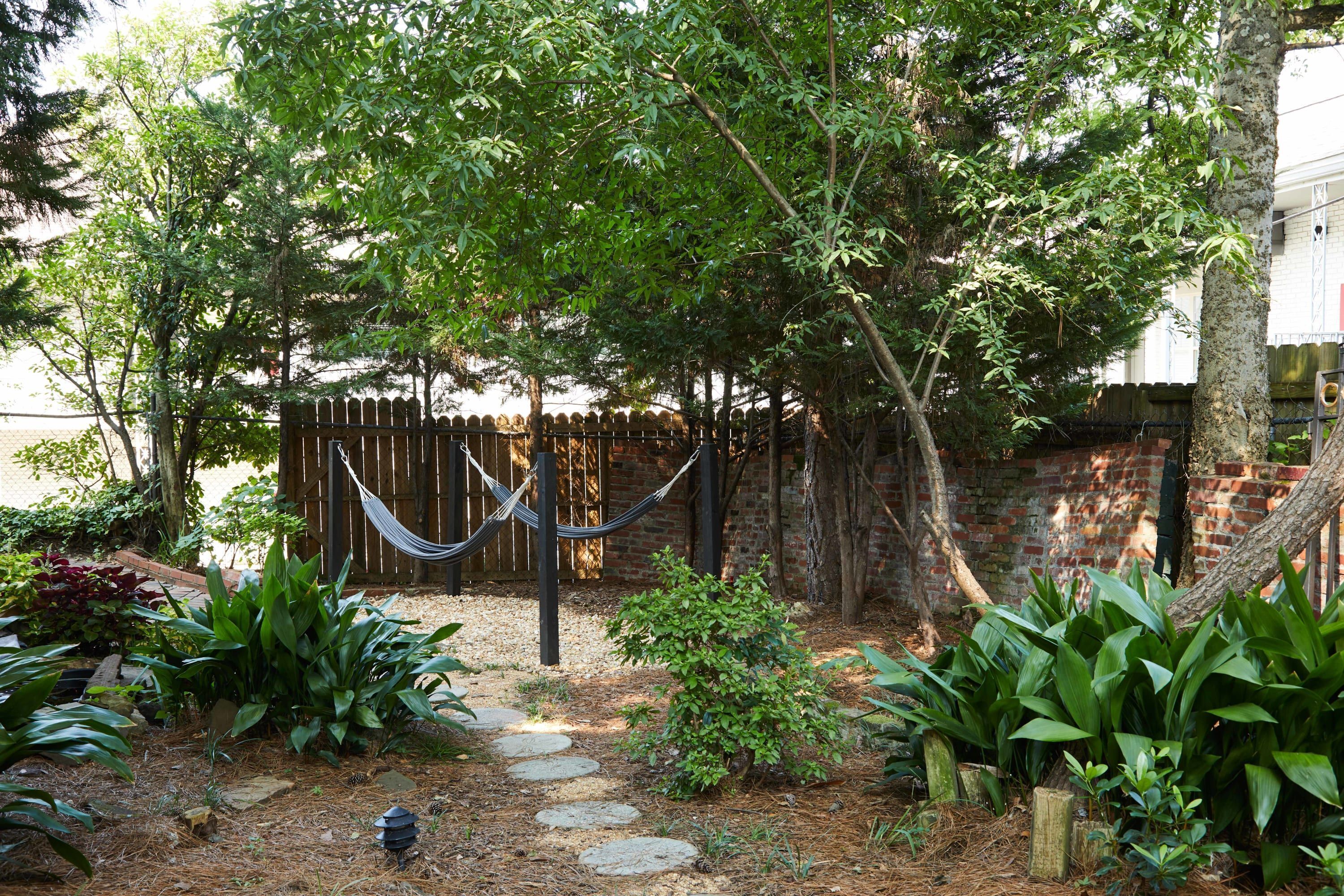 A garden with a hammock, stepping stones, and various plants.