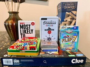 Una colección de juegos de mesa, incluyendo UNO, Dominoes, JUMPING TOWER y FLIP7, mostrados sobre una mesa.