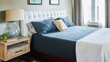 A bedroom with a large bed, a nightstand with a lamp, and two framed pictures on the wall.