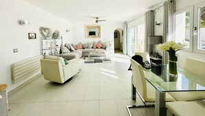 Una sala de estar moderna con sofá, mesa de centro y mesa de comedor de vidrio.