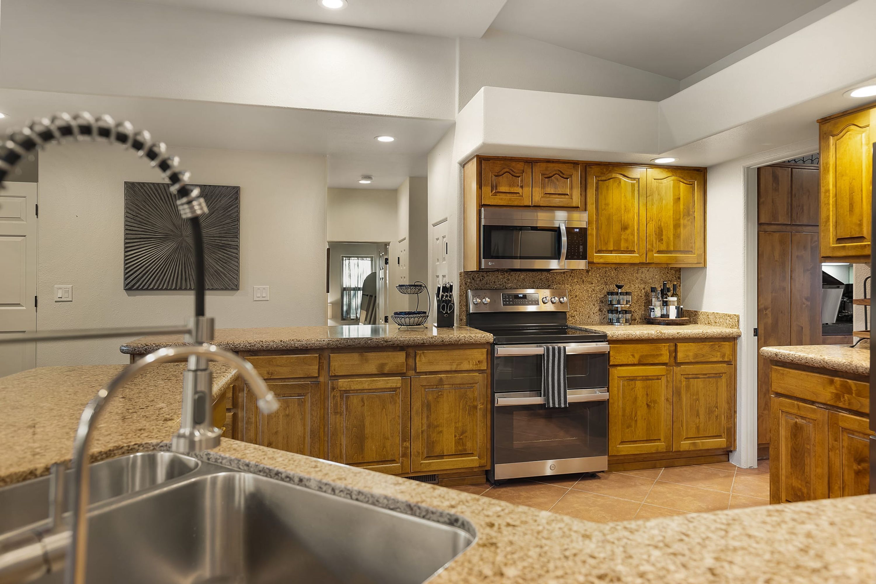 A modern kitchen with granite countertops, stainless steel appliances, and wooden cabinets.