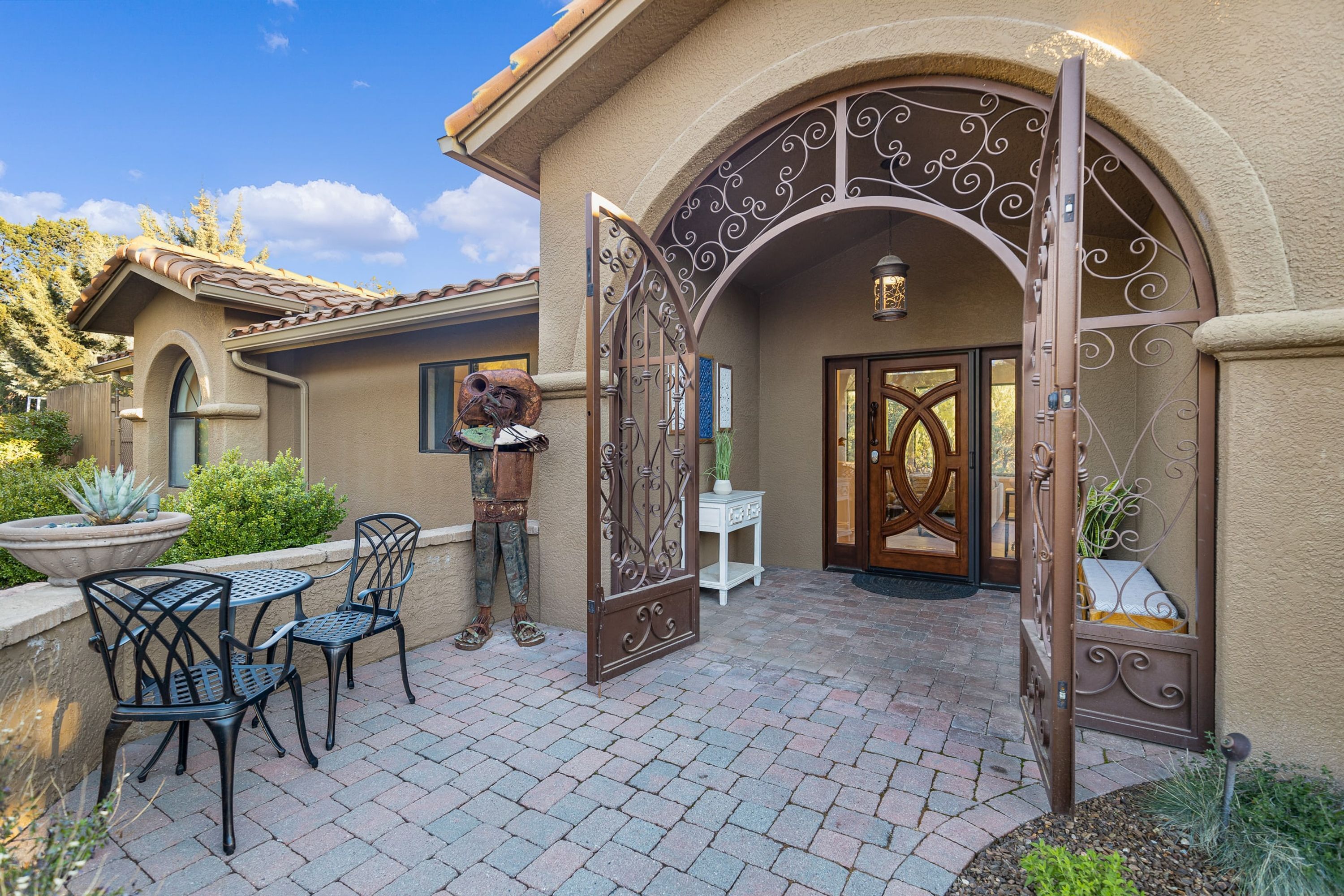 A patio with outdoor furniture, a decorative gate, and a well-maintained garden.