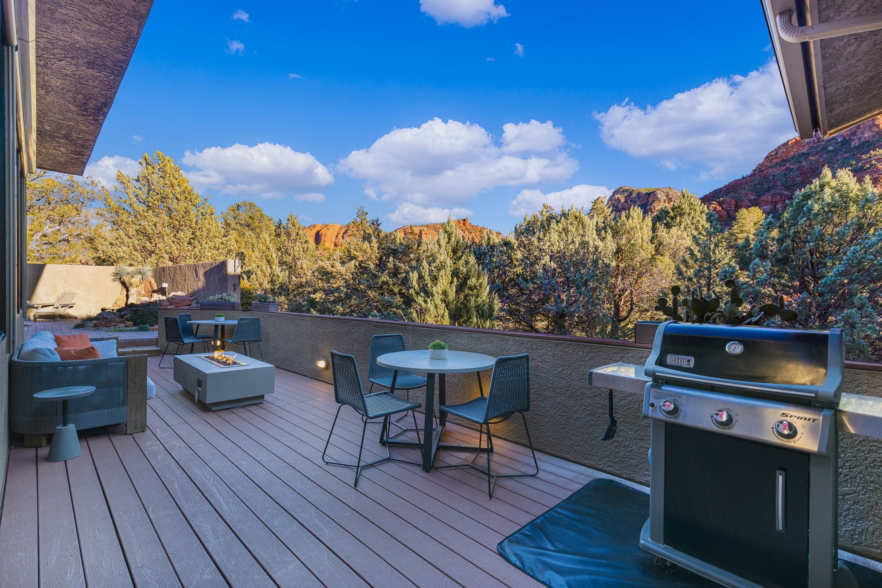 An outdoor patio with a grill, seating area, and a view of a mountainous landscape.
