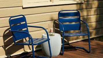 Una terraza de madera con dos sillas azules y una mesa redonda blanca.