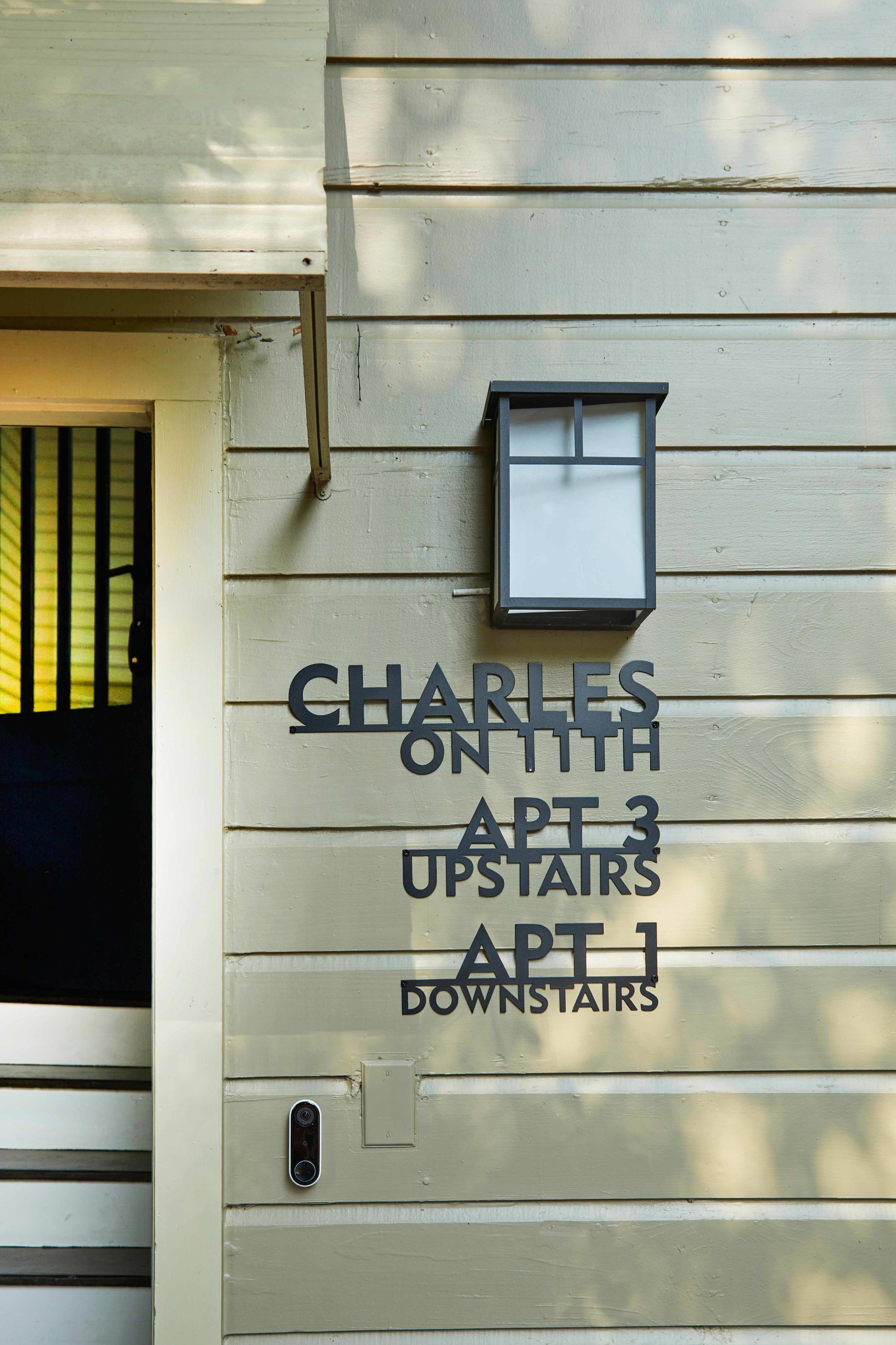 A building with a sign indicating 'CHARLES ON 11TH APT 3 UPSTAIRS APT 1 DOWNSTAIRS.'