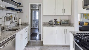 Une cuisine moderne avec des armoires blanches, des appareils en acier inoxydable et un comptoir en granit.