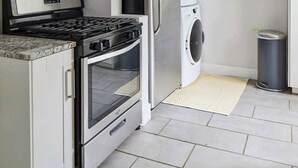 Une cuisine moderne équipée d’appareils électroménagers en acier inoxydable, d’un four à micro-ondes, d’un four et d’un lave-linge et d’un sèche-linge intégrés.