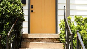 Une porte jaune avec une petite fenêtre, une boîte aux lettres et le numéro 24 peint sur le mur.