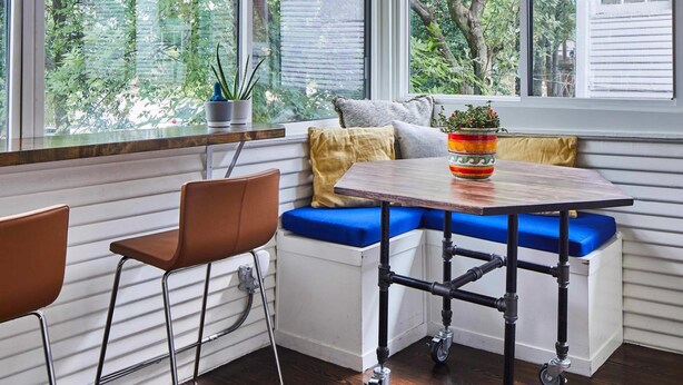 A corner seating area with a table and chairs, large windows with a view of trees, and a hanging light fixture. - Apt3 Charles - Modern Fun Sun-filled Loft (Birmingham)