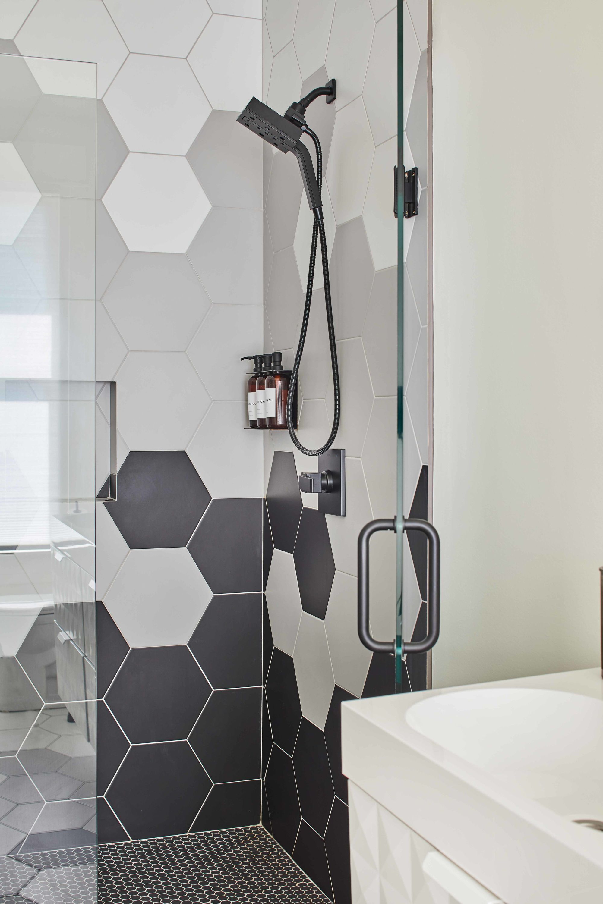 Un baño moderno con ducha, mampara de vidrio y lavamanos blanco.