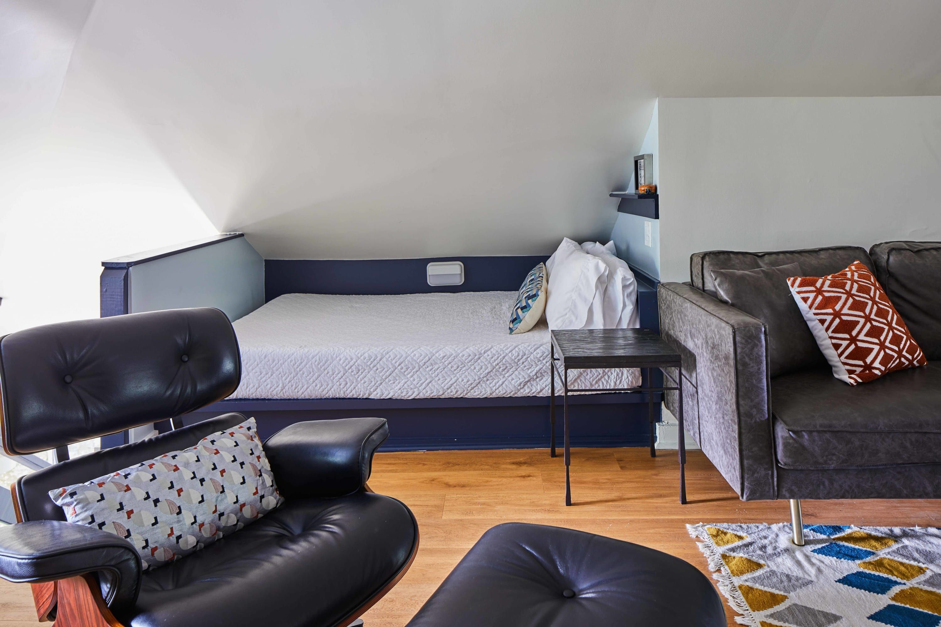 A room with a bed, a sofa, a chair, and a small table.