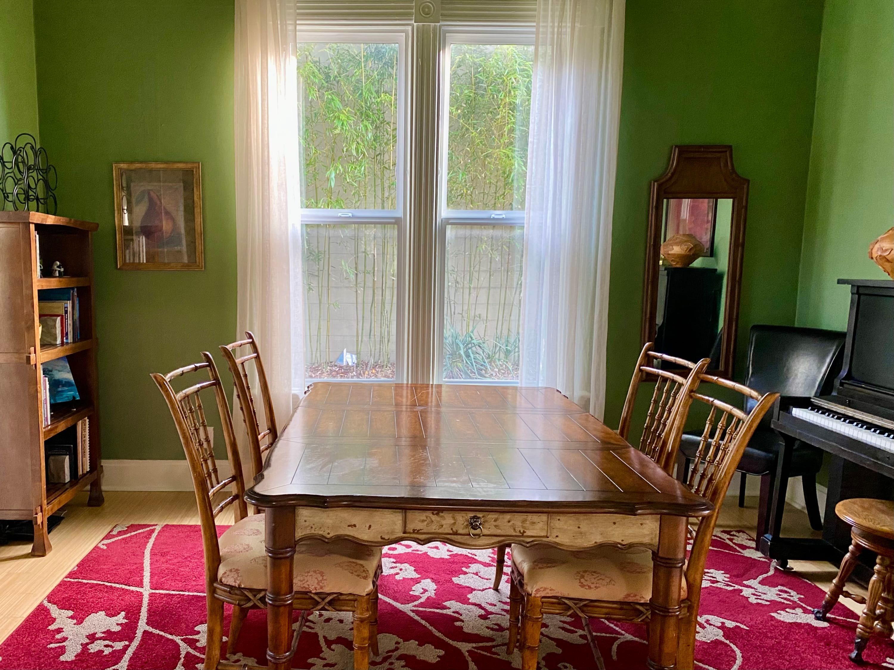 Ein Esszimmer mit Holztisch und -stühlen, einem Klavier und einem Bücherregal.