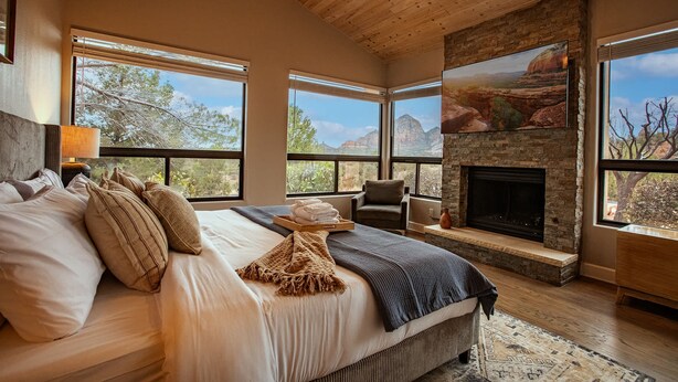 A bedroom with a large bed, a fireplace, and a view of the mountains.