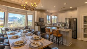 A modern kitchen with white cabinets, a central island, and a dining area set for six.