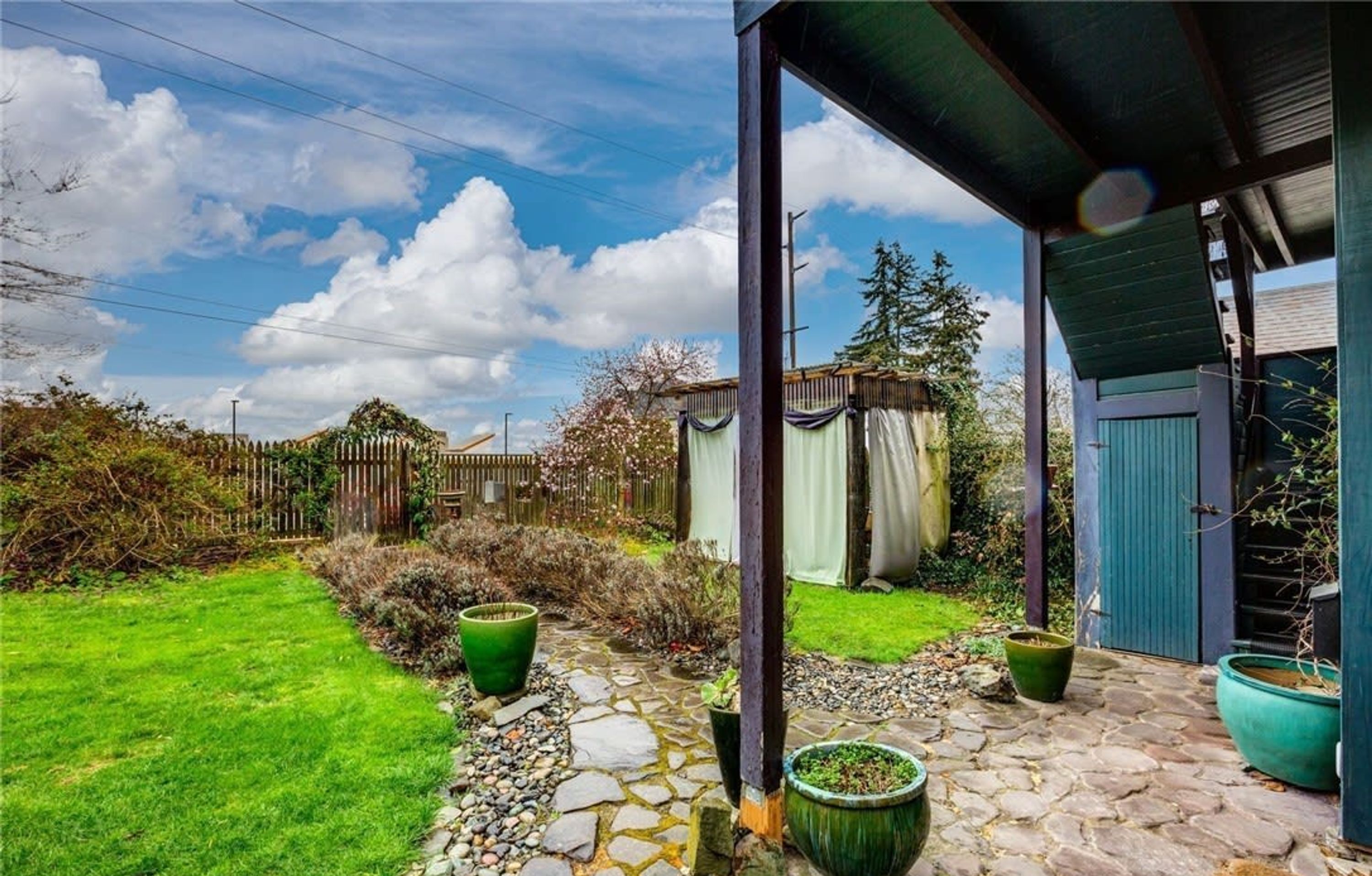 A stone pathway leading to a covered porch with potted plants.