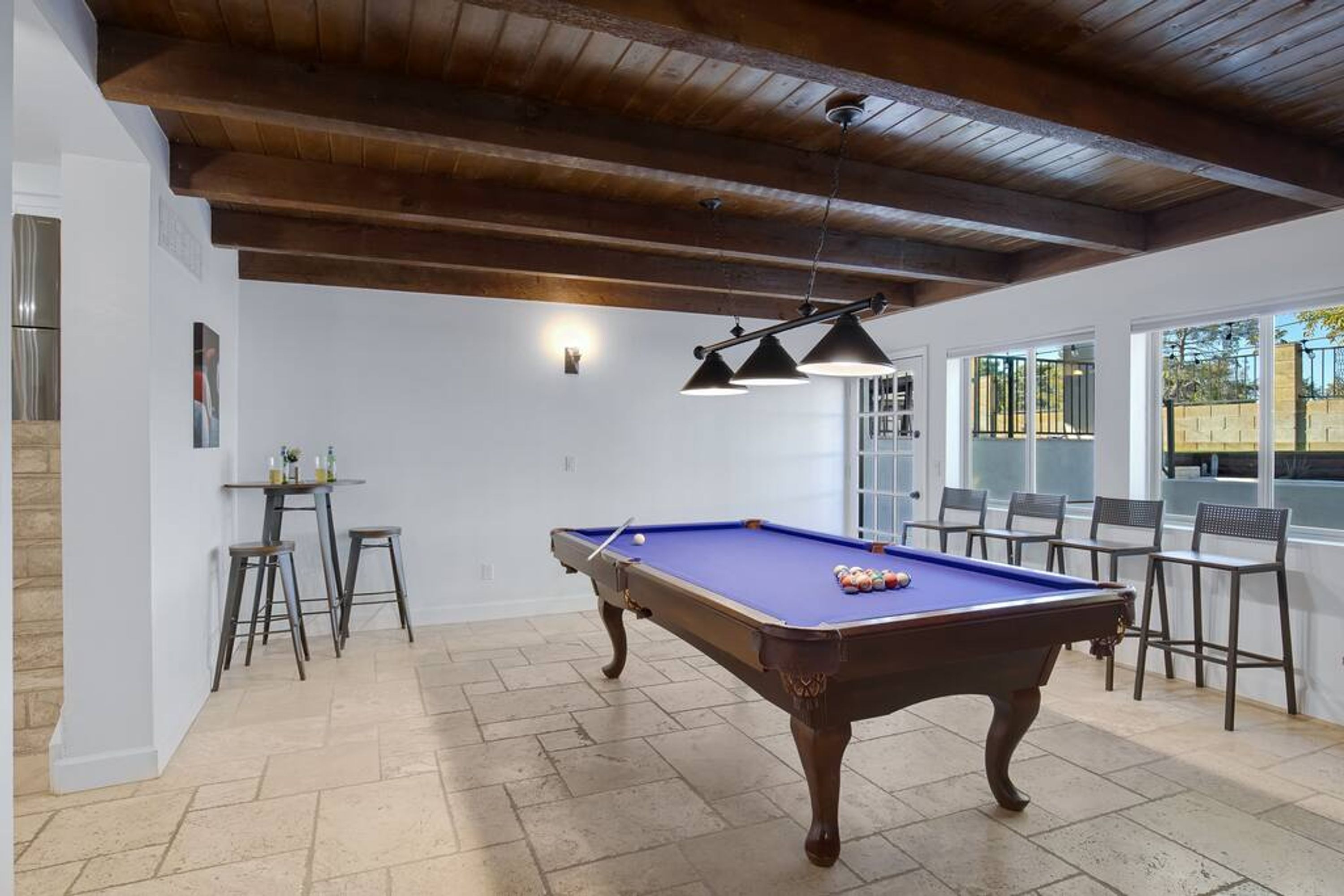 A pool table in a room with a wooden ceiling and stone flooring.