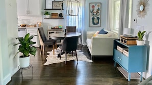 A modern kitchen with white cabinets, a dining table with chairs, and a blue cabinet with shelves. - Blue Door Walk to Avondale Dog-friendly w Yard (Birmingham)
