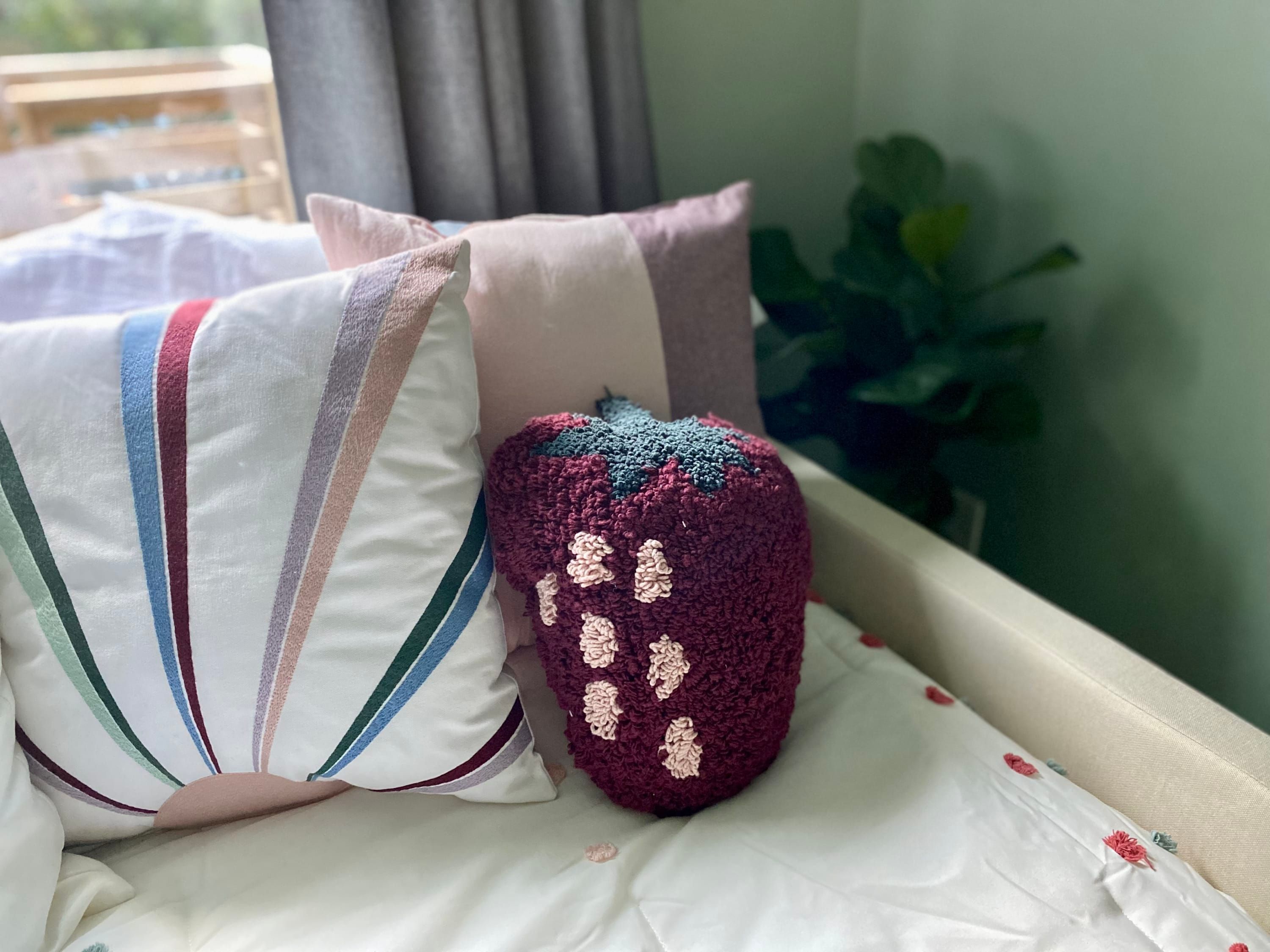 A bed with striped pillows and a crocheted pillow.