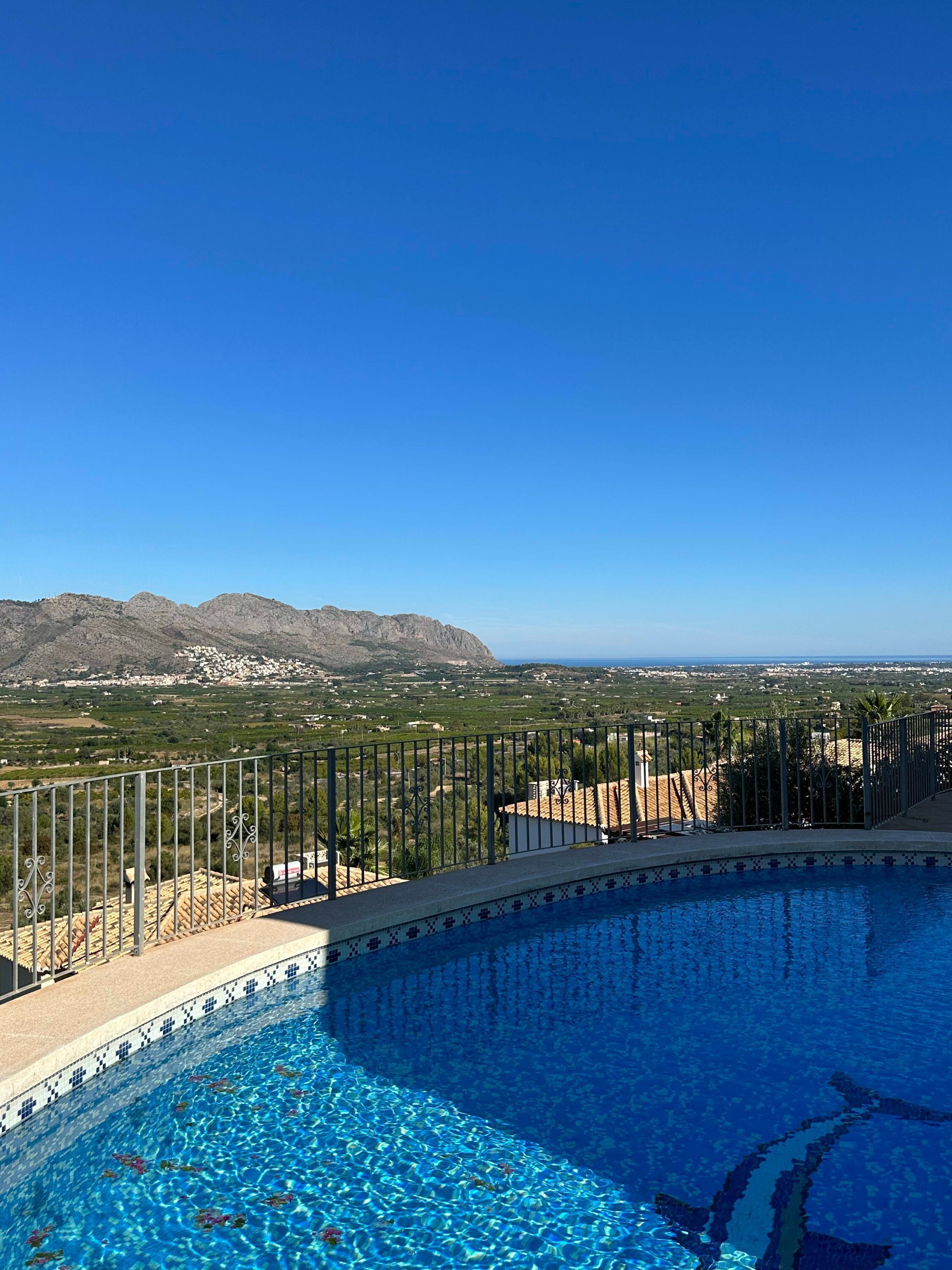 A swimming pool with a view of a mountainous landscape and a distant city.