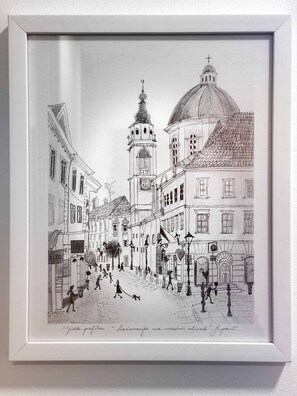 Een lijst met een zwart-wit schets van een straatbeeld met gebouwen, een klokkentoren en mensen die lopen.