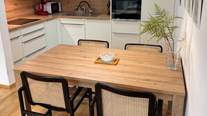 Een moderne keuken met witte kasten, een houten eettafel en een hangende吊灯.