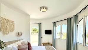 A spacious bedroom with a large bed, a television on the wall, and a view through the window. - 3 Bedroom Villa Walking Distance to Moraira (Teulada)