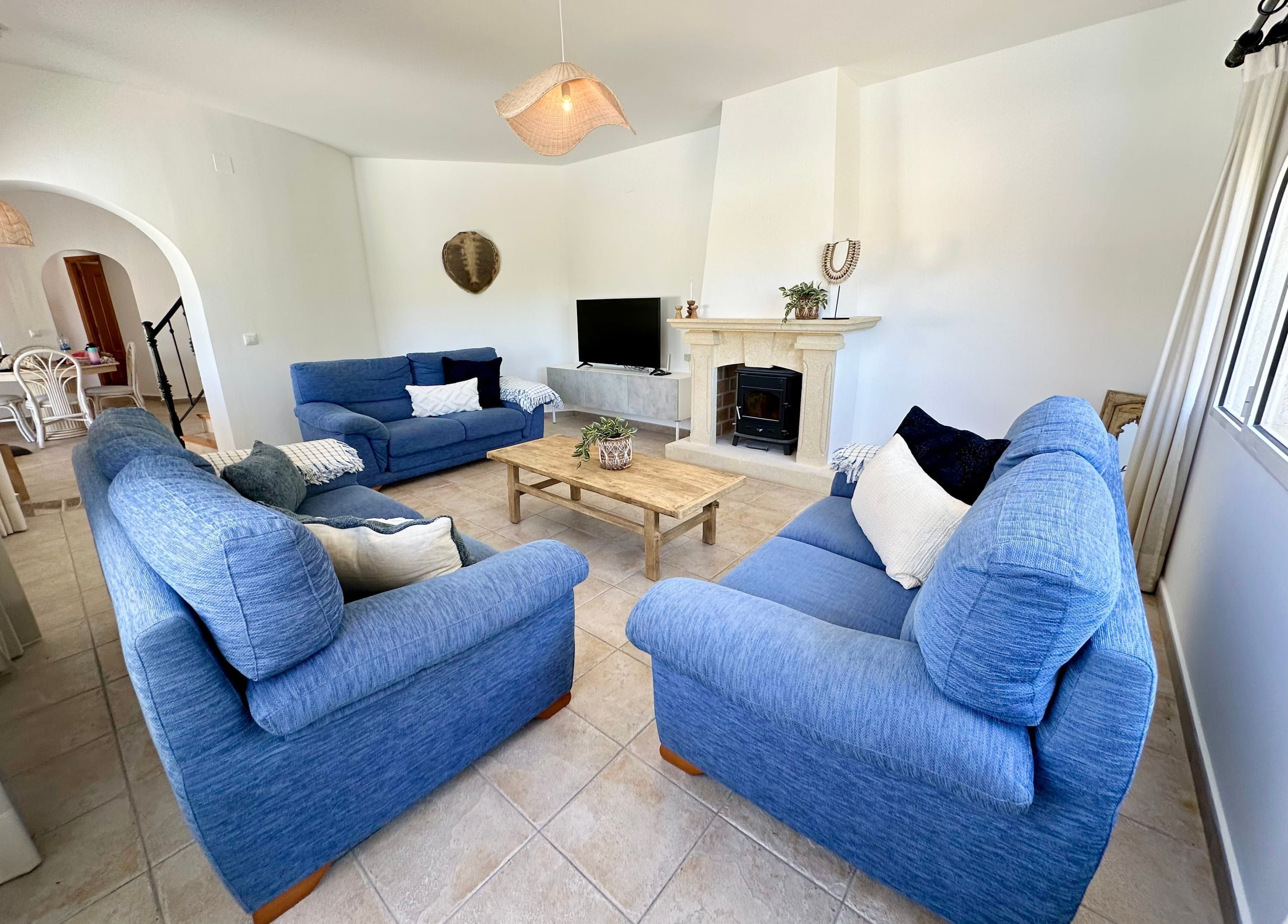 A living room with two blue sofas, a wooden coffee table, a fireplace, and a TV.