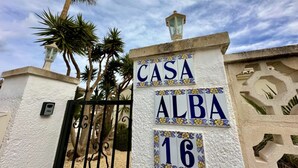 A white wall with the text "CASA ALBA 16" in blue and yellow decorative tiles, a black metal gate, and a palm tree in the background. - Three Bedroom Villa With Private Pool in Moraira (Teulada)