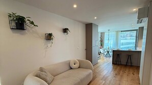 A modern living space with a sofa, wooden flooring, and a kitchen area with stools. - Skyline Penthouse Retreat Luxury in Ljubljana (Ljubljana)