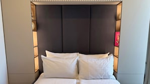 A neatly made bed with white linens and two rolled towels, a dark headboard, and a wall with vertical lines. - Skyline Penthouse Retreat Luxury in Ljubljana (Ljubljana)