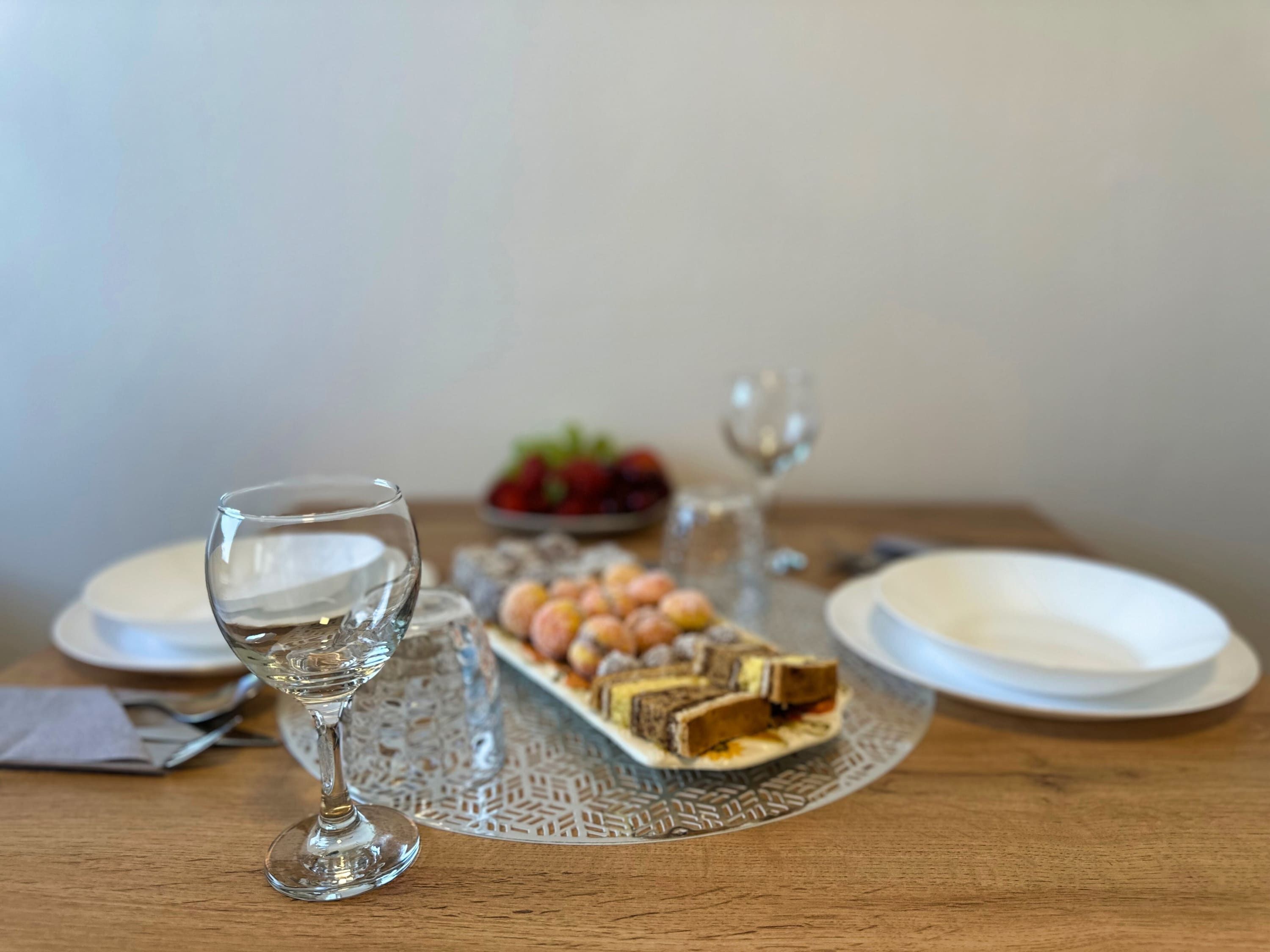 Una mesa de comedor con un vaso de agua, un plato de pasteles y un tazón de fruta.