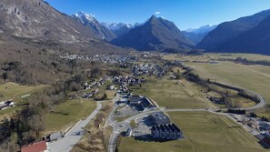Une vue aérienne d’une ville avec un bâtiment central, entouré de montagnes et de vastes champs.