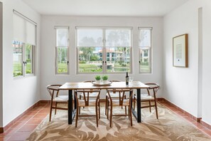 A dining area with a table and chairs, large windows with blinds, a rug, and a framed picture on the wall. - Upscale Villa in Gated Community Beach Access Yari (Vega Alta)