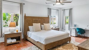 Une chambre à coucher avec un grand lit, un bureau, une chaise et un ventilateur de plafond.
